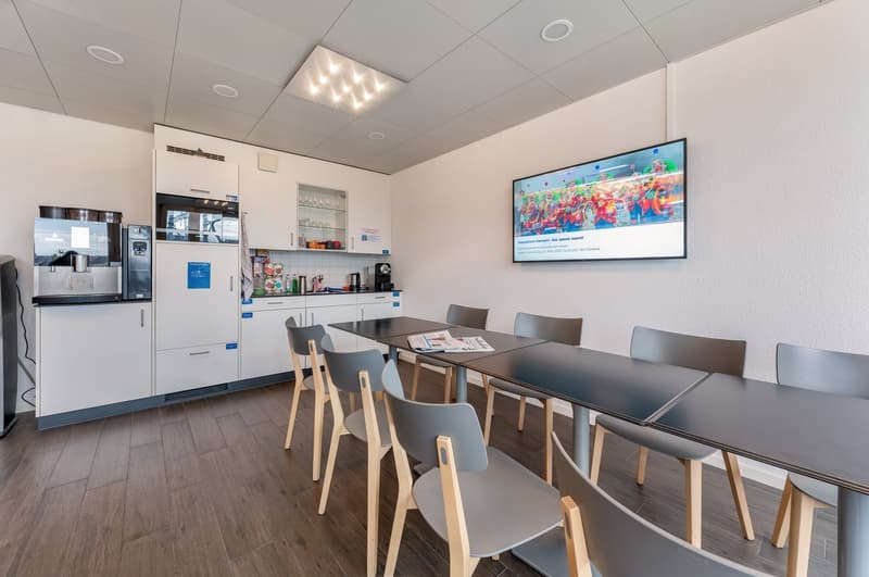 modern kitchen area with appliances, dining table with chairs, flat screen TV on wall