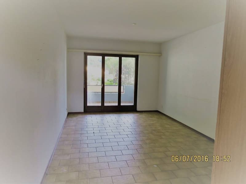 empty room, white walls, wooden tiles on the floor, glass sliding doors with a balcony, bright light