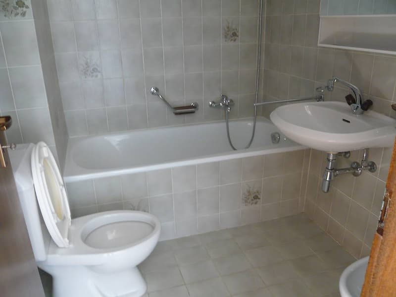 Bathroom with bathtub, sink, toilet, bidet, tiled walls, white fixtures