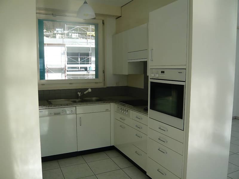 modern kitchen with white cabinets, tiled floor, sink, dishwasher, oven, window