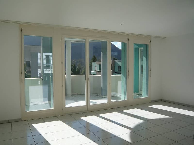 empty room, white walls, white tiles, large glass sliding doors, balcony, mountain view