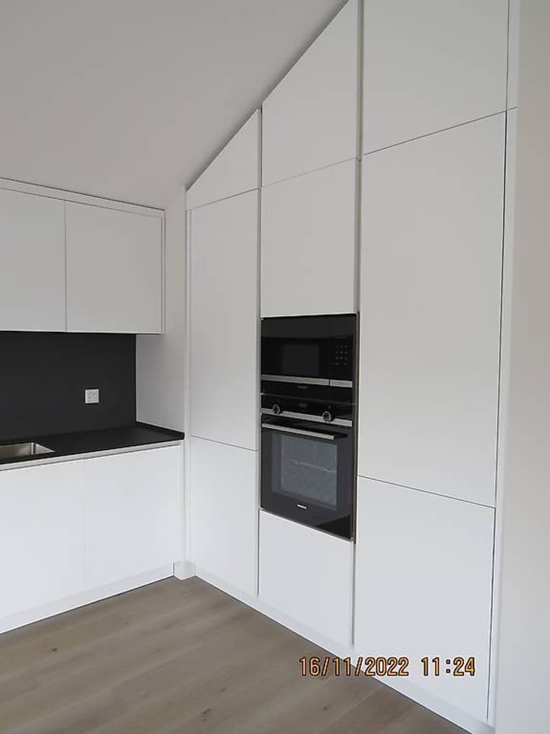white cabinets, wooden floor, black countertop, integrated oven and microwave, stainless steel sink, electrical socket, modern design