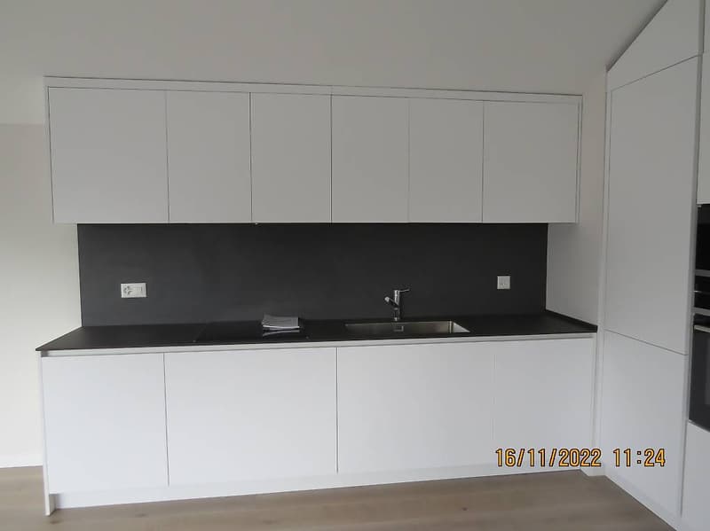 kitchen with white cabinets, black countertops, stainless steel sink and faucet, wooden floor