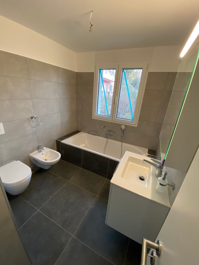 Bathroom with white toilet, bidet, bathtub, and sink.
