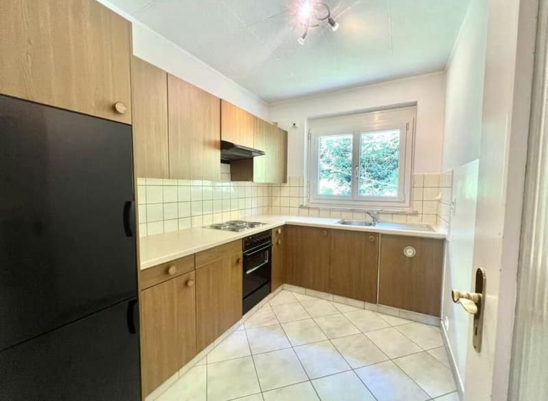 kitchen with wooden cabinets, tile flooring, white appliances, gas stove, sink, window