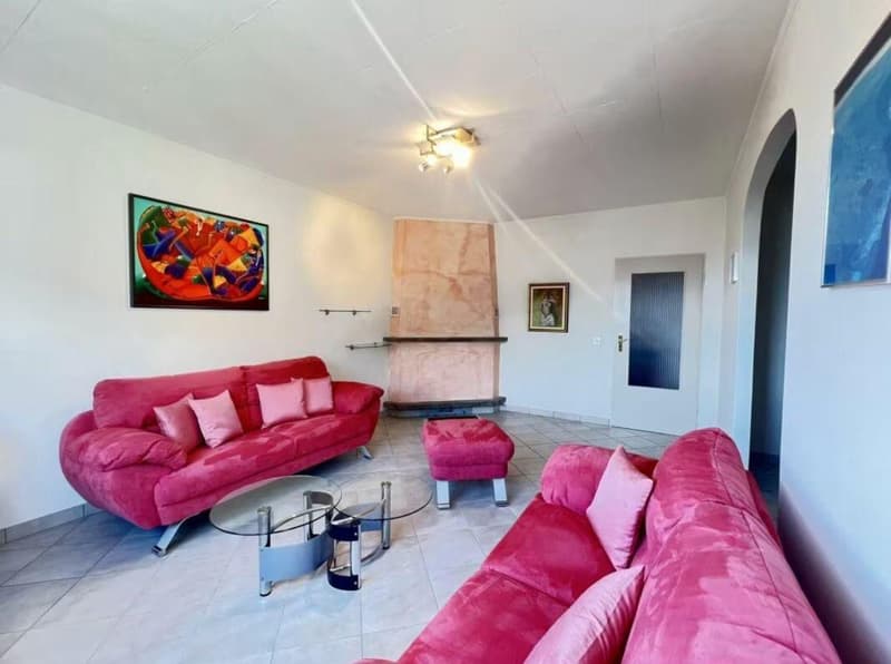 Fireplace, two pink sofas, ottoman, glass table, white tile flooring, paintings