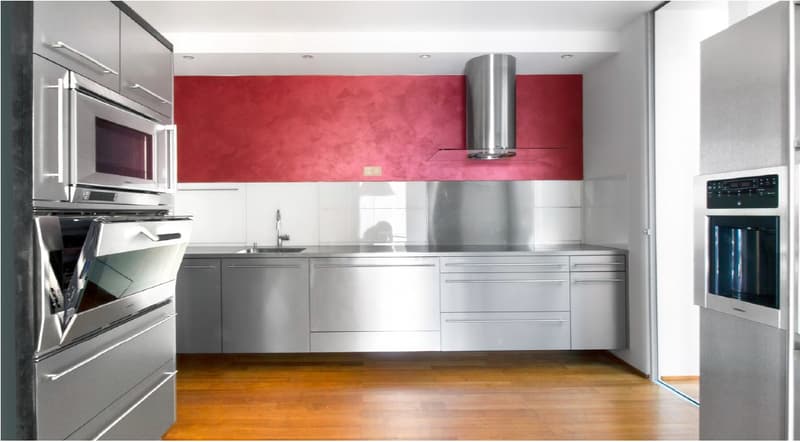 Modern kitchen with red painted wall, stainless steel appliances, wooden floors