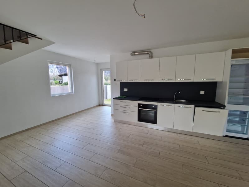 modern kitchen with white cabinets, black countertops, stainless steel sink, oven, refrigerator, wooden floor