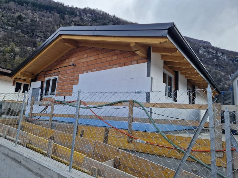 House under construction, brick walls, wooden roof, windows, metal fence, construction materials