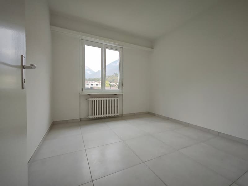 empty room with white tiled floor, white walls, a window with a view, white radiator