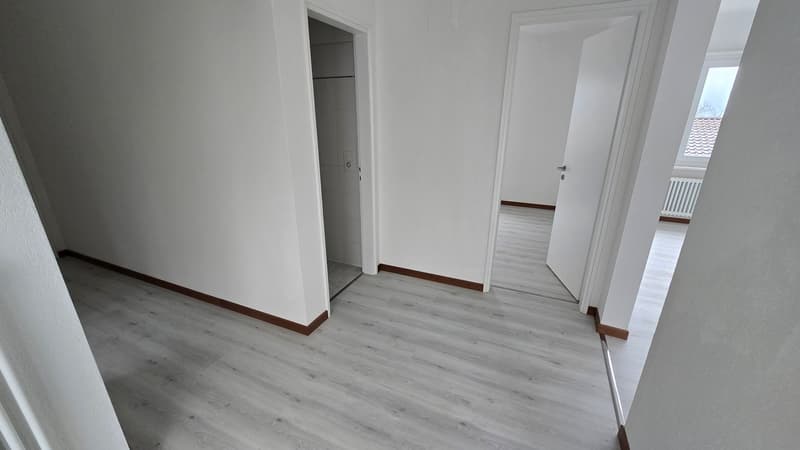 Empty room, white walls, hardwood floor, no windows, doors leading to other rooms