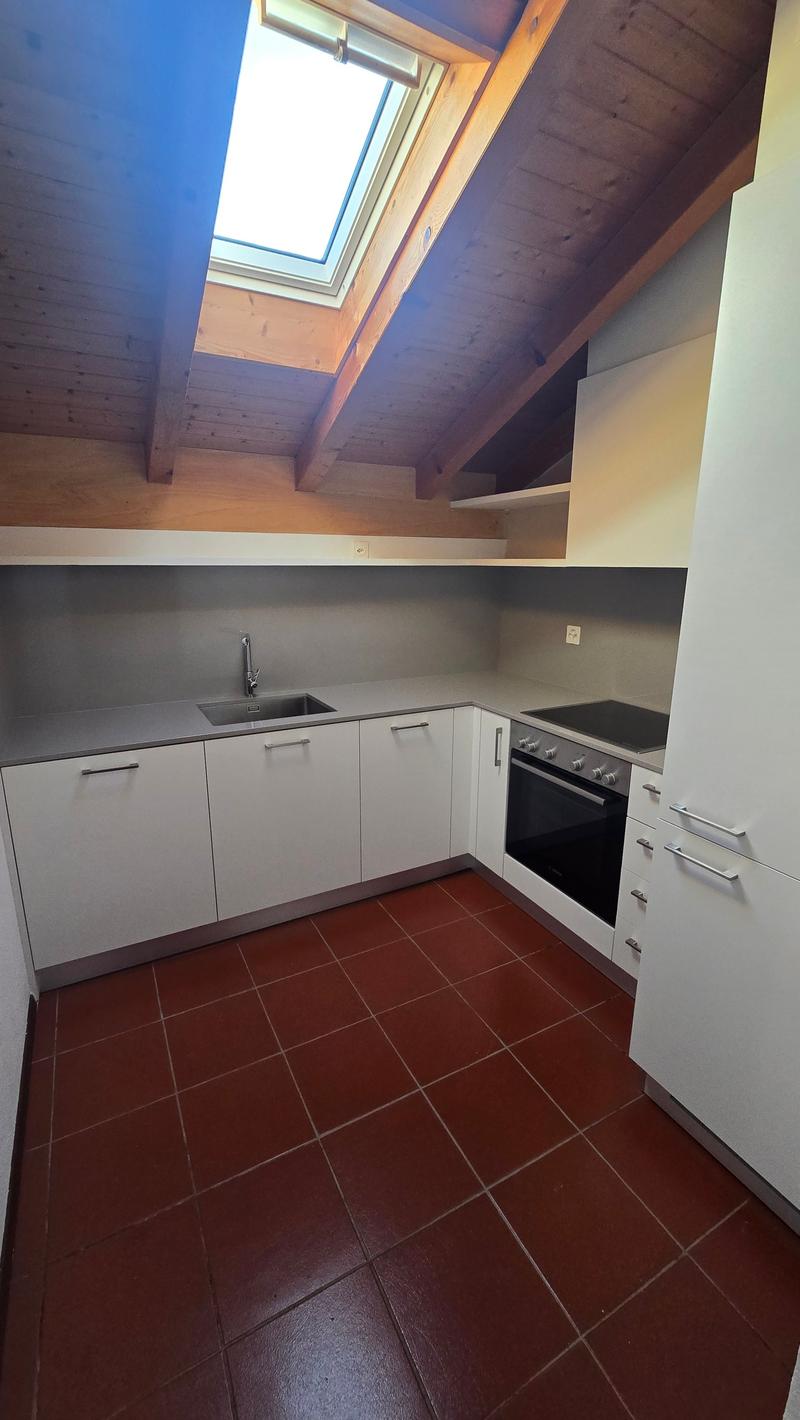 modern kitchen with white cabinets, red tiles, stainless steel sink, oven, and a skylight
