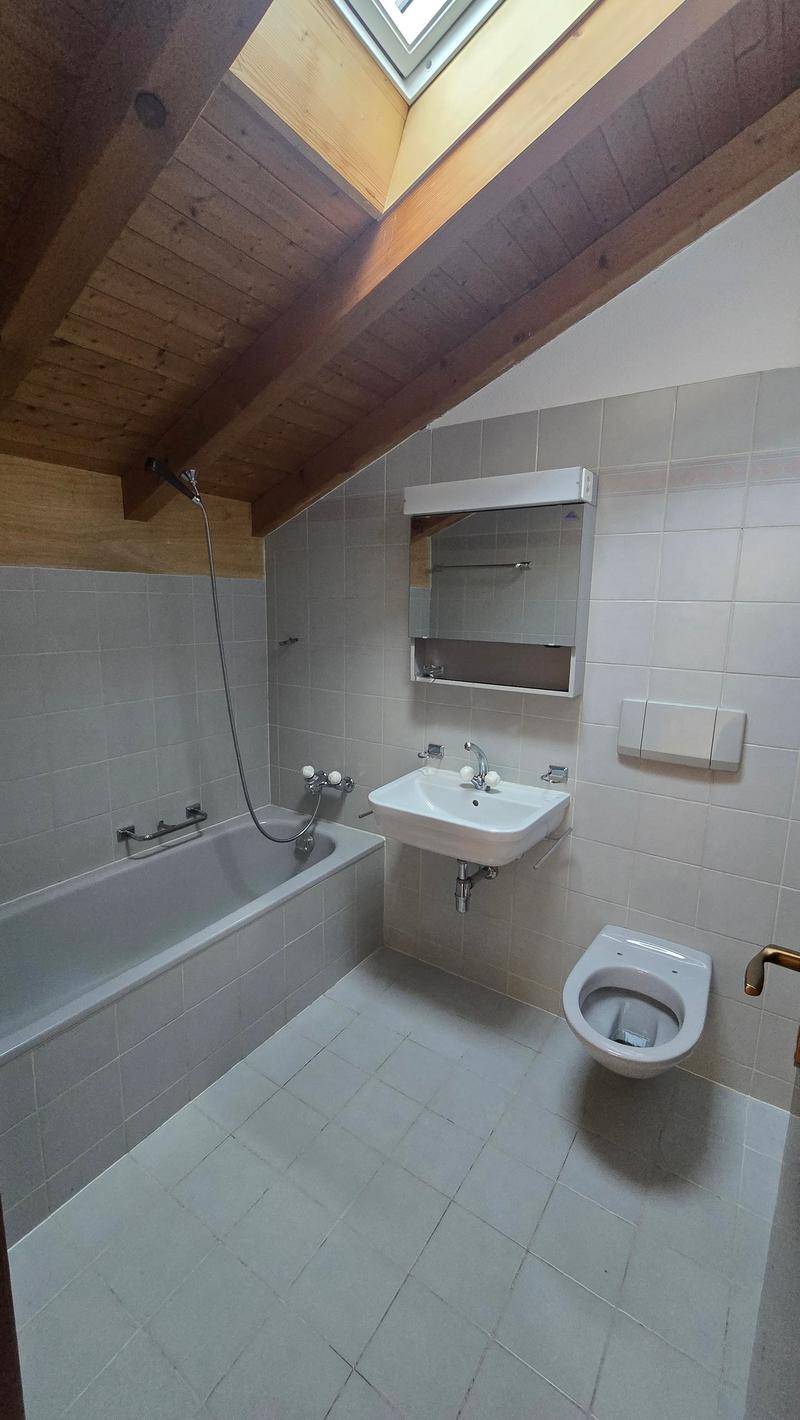 Bathroom with bathtub, sink, toilet, wooden ceiling, white tiles, mirror, shower head