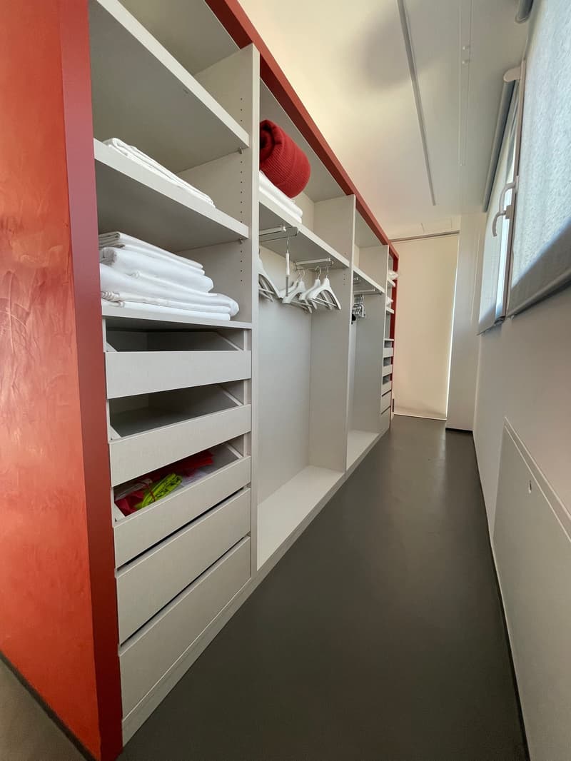 A well-organized closet with multiple shelves and drawers; a red blanket on top of the closet