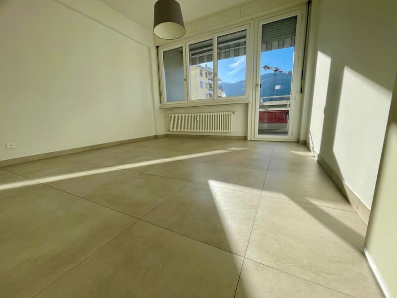 empty room, sliding doors to balcony, windows, white walls, white tile flooring