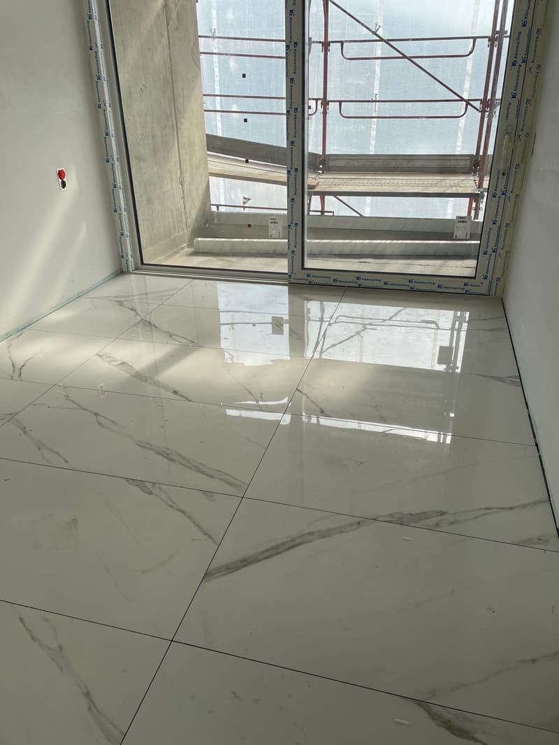 white marble flooring, glass door, white walls, red button on wall