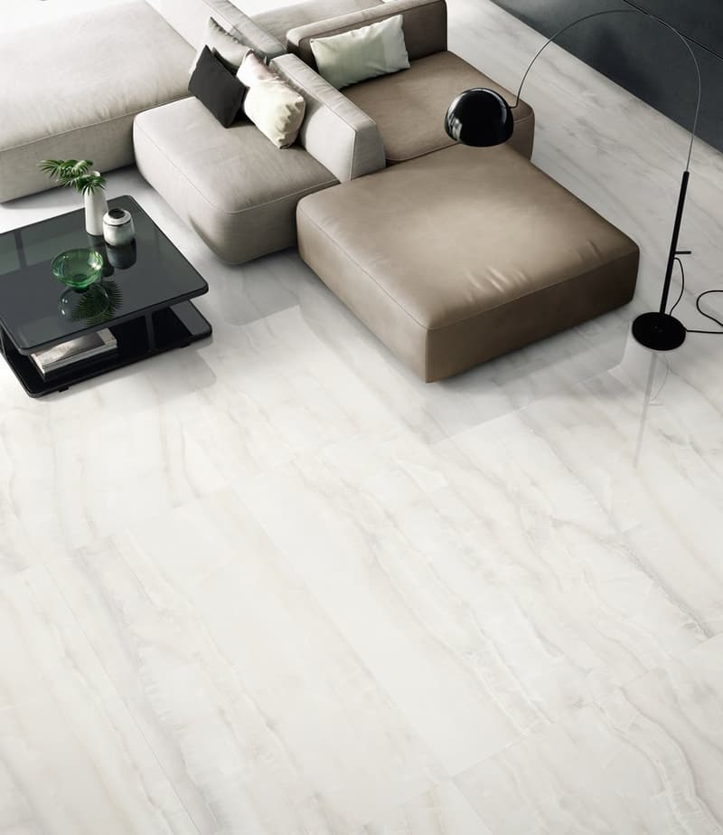 Marble flooring, modular sectional sofa, glass coffee table, floor lamp, plant in white vase.