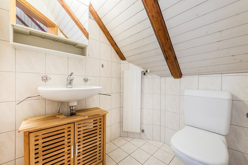 bathroom with wooden beams, white tiles, toilet, sink, radiator, wooden cabinet