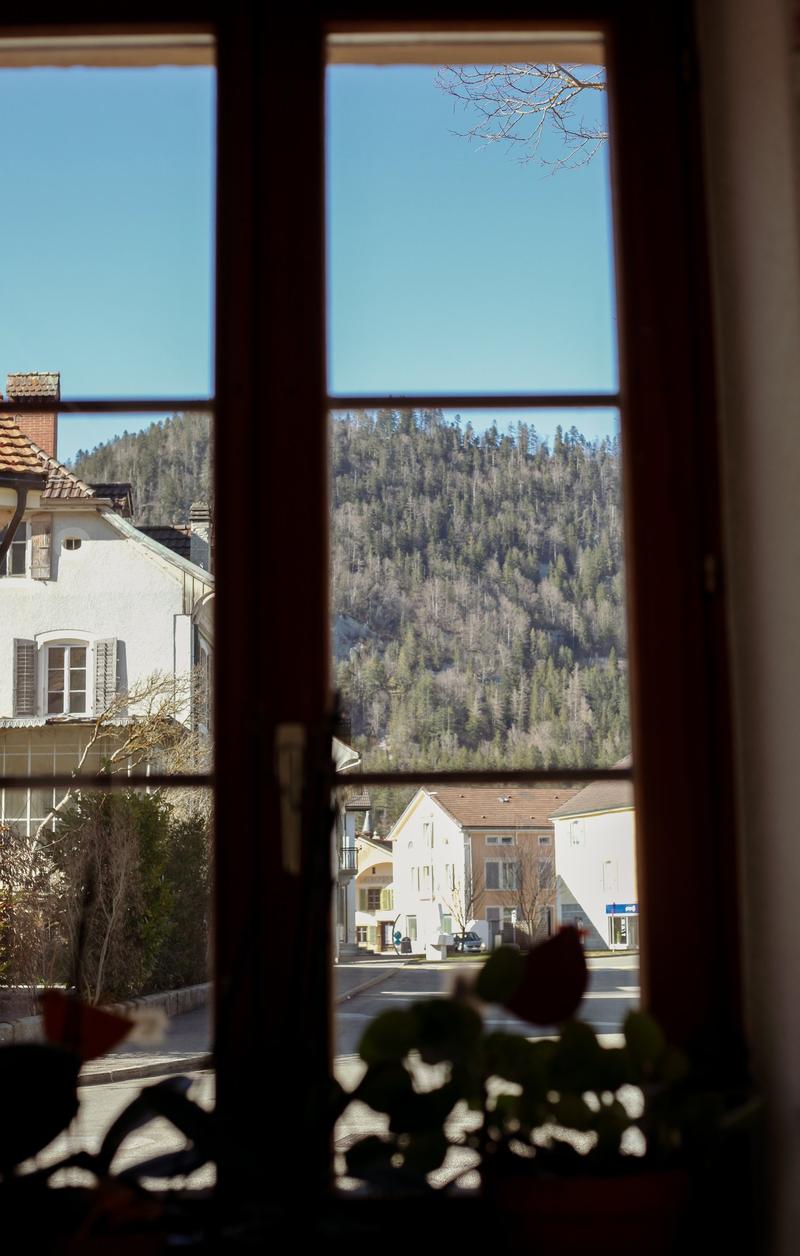 View from a window overlooking a mountain landscape, with buildings in the foreground.