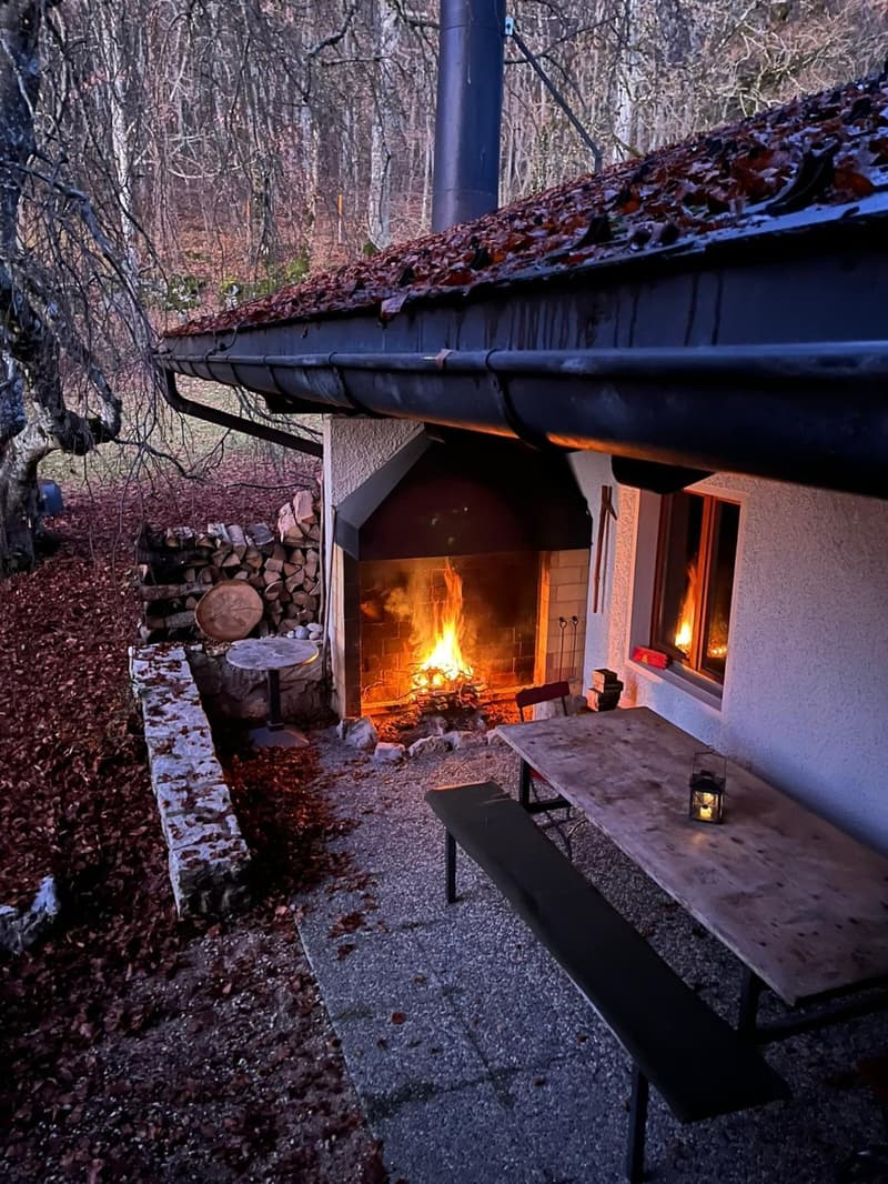 Outdoor fireplace, bench, table, window with fire glowing inside
