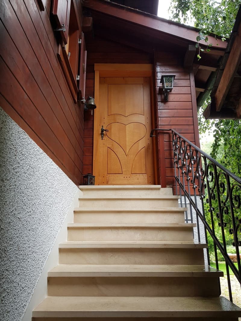 wooden house, stone steps, wooden door with heart design, wrought iron railing