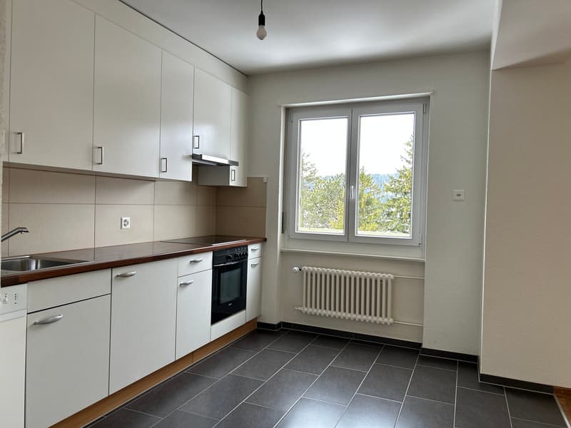 modern kitchen with white cabinets, black tiled floor, stainless steel sink, electric oven, window with view