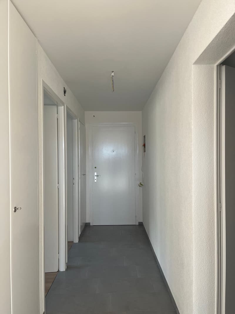 empty corridor, white walls, tiled floor, doors, power outlet