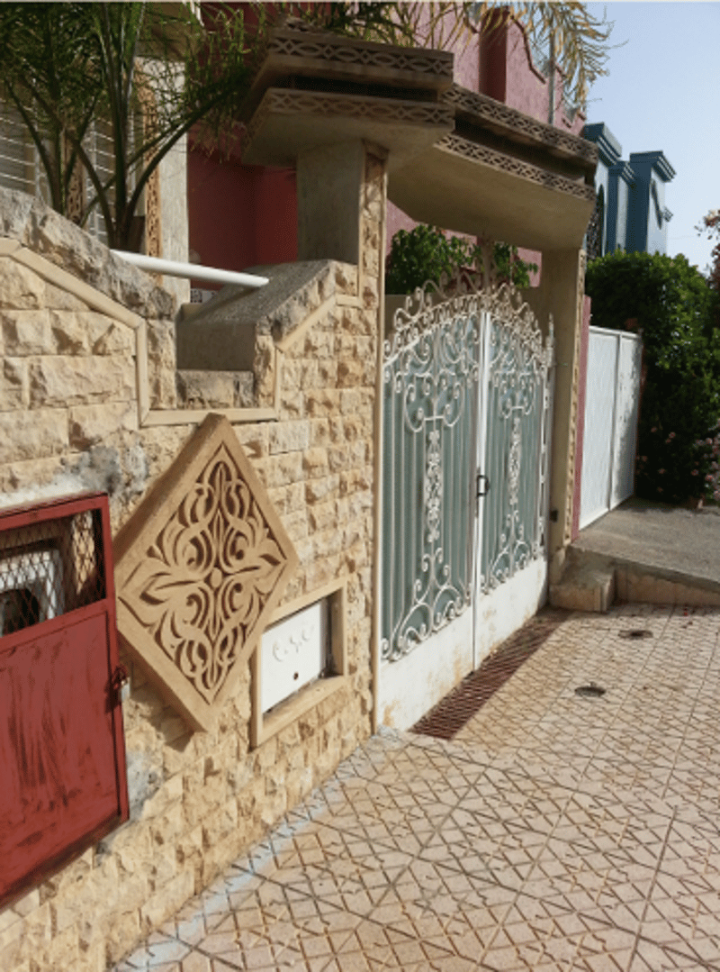 brick wall, decorative wall inlay, closed wrought iron gate, and a small window beneath