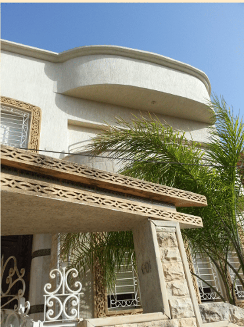 two story building, white stone walls, palm trees, glass windows, wooden entrance