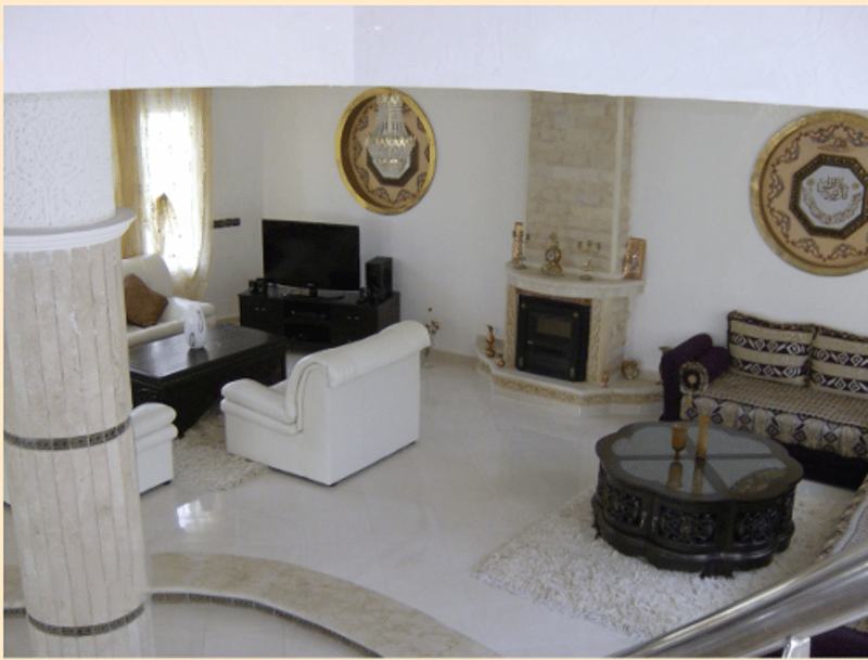Living room, fireplace, glass top coffee table, two couches, TV, decorative wall decor, carpet, white walls