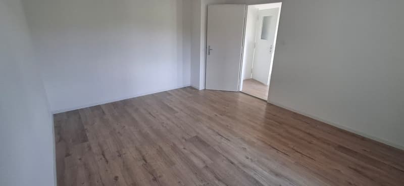 empty room, hardwood floors, white walls, an open door leading to another room