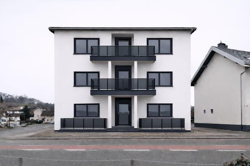 3 story building, white walls, black trim, glass balconies, black railings