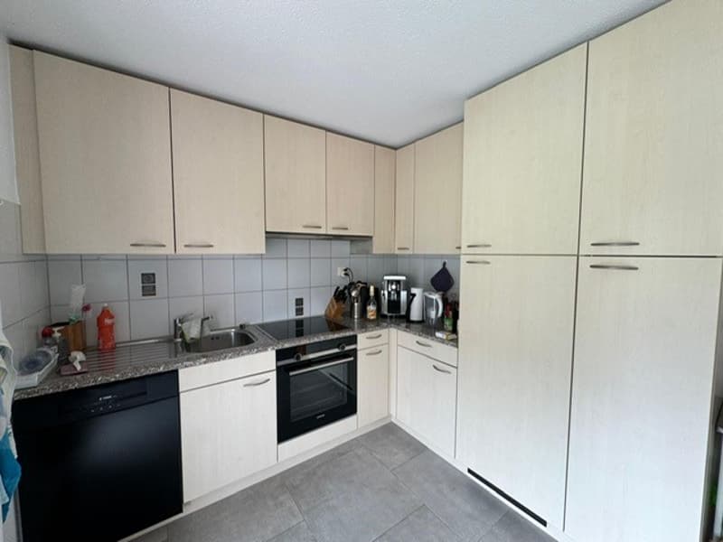 modern kitchen, wooden cabinets, black appliances, tiled floor, countertop with sink, oven, dishwasher