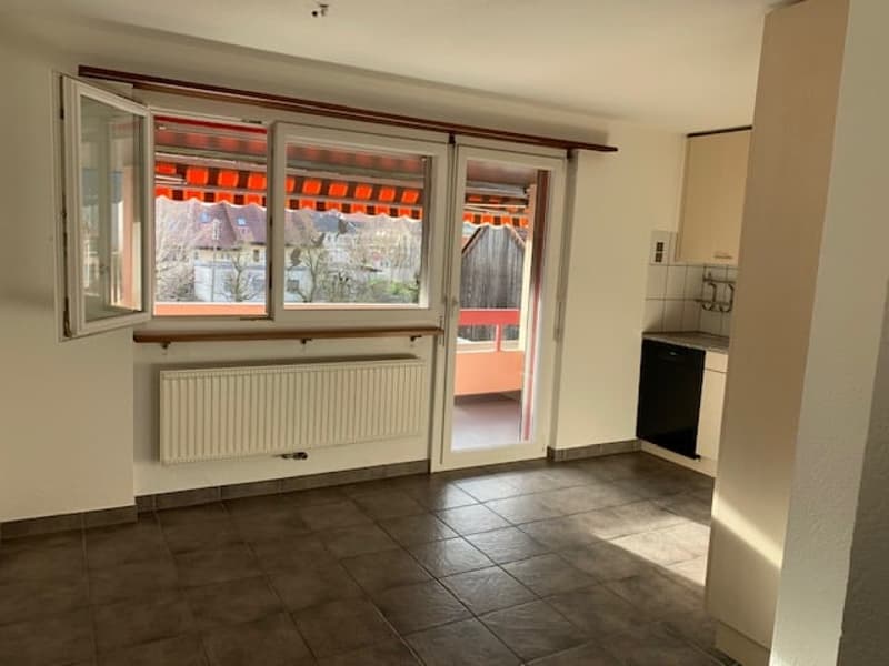 empty room with balcony, large windows, tile floor, kitchen area, white radiator