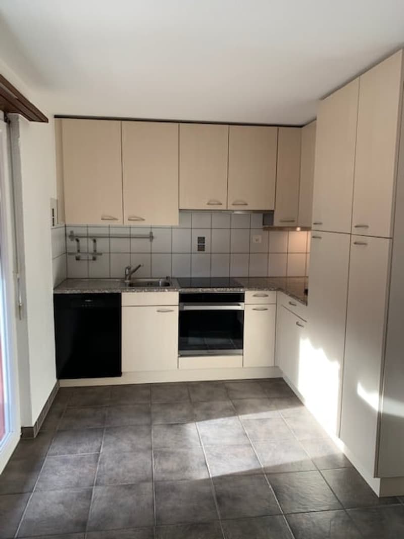 Modern kitchen with built-in appliances, tiled floor, and overhead cabinets