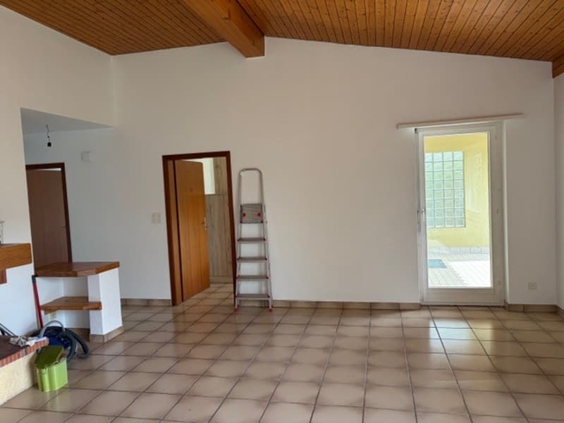 empty room, tiled floor, wooden ceiling, white walls, wooden door, glass door, ladder, green trash bin