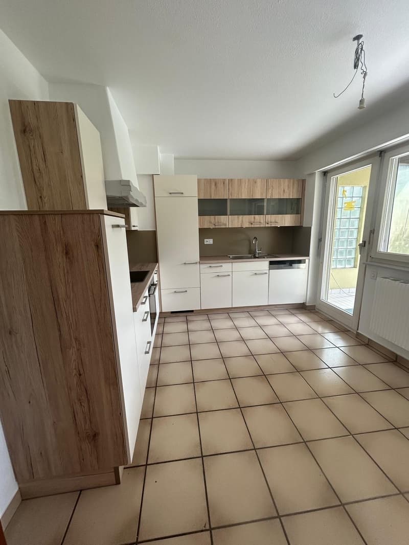 modern kitchen with wooden cabinets, tiled floor, sink, dishwasher, and a sliding door leading to a balcony