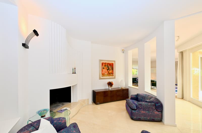 modern white walls, hardwood floors, fireplace, two abstract couches, glass table, picture frame