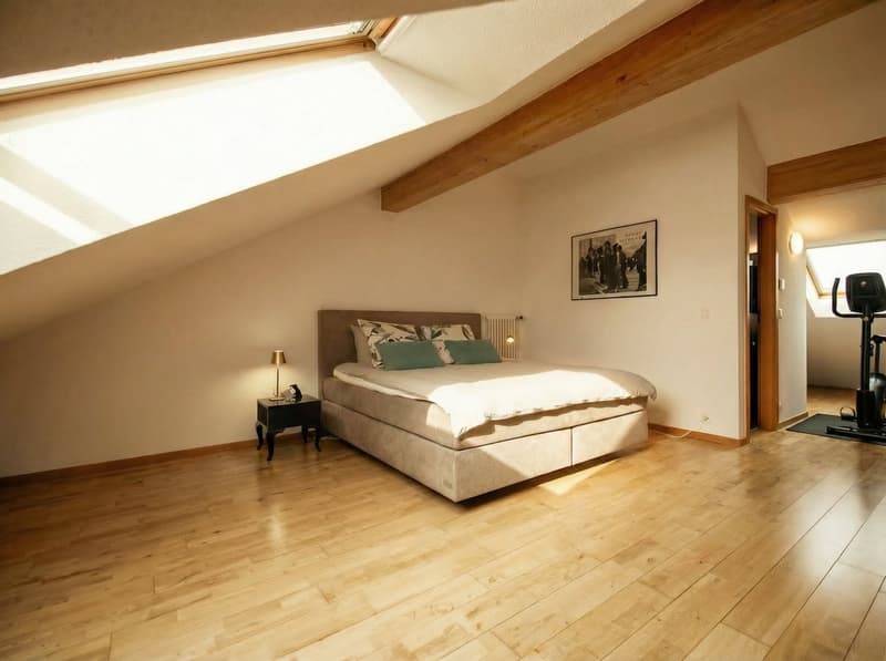 Bedroom with wooden floor, bed, nightstand, lamp, picture frame, and exercise equipment
