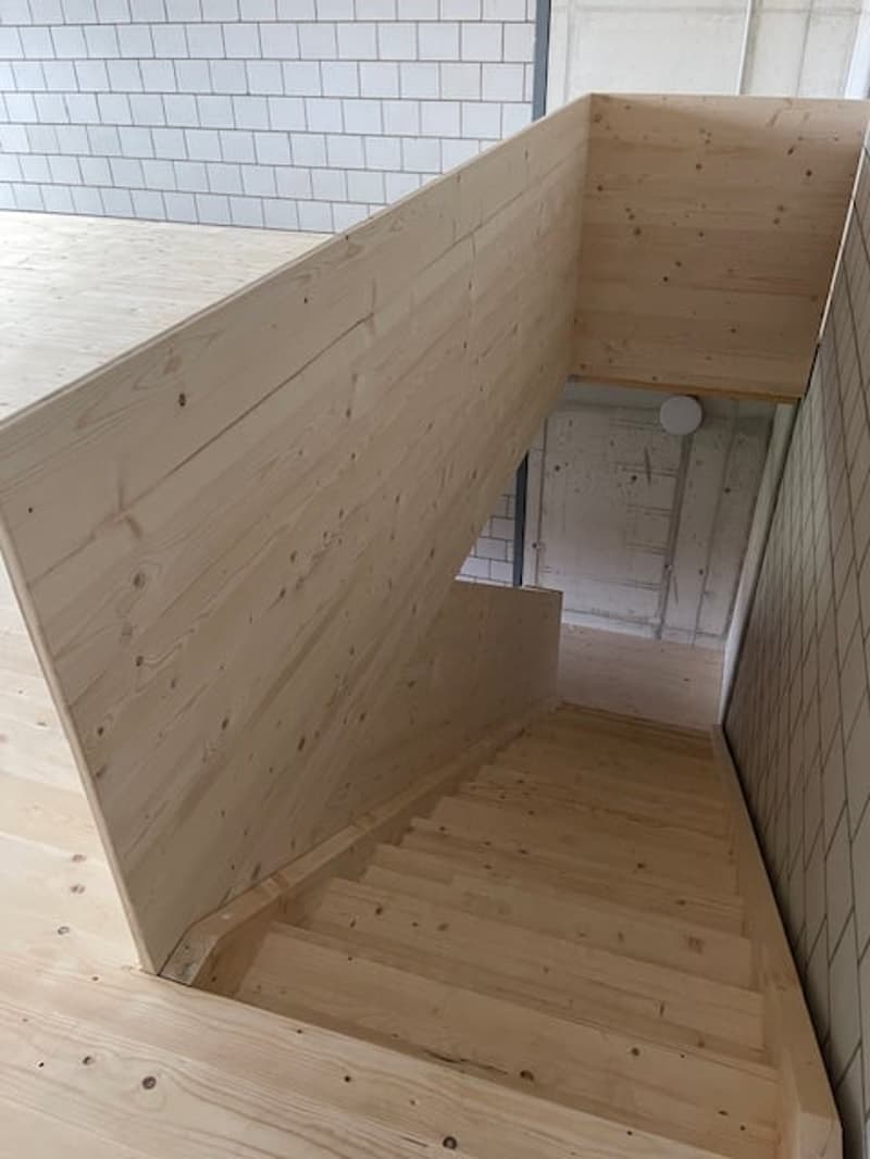 Wooden staircase, white tiled walls, raised ground floor