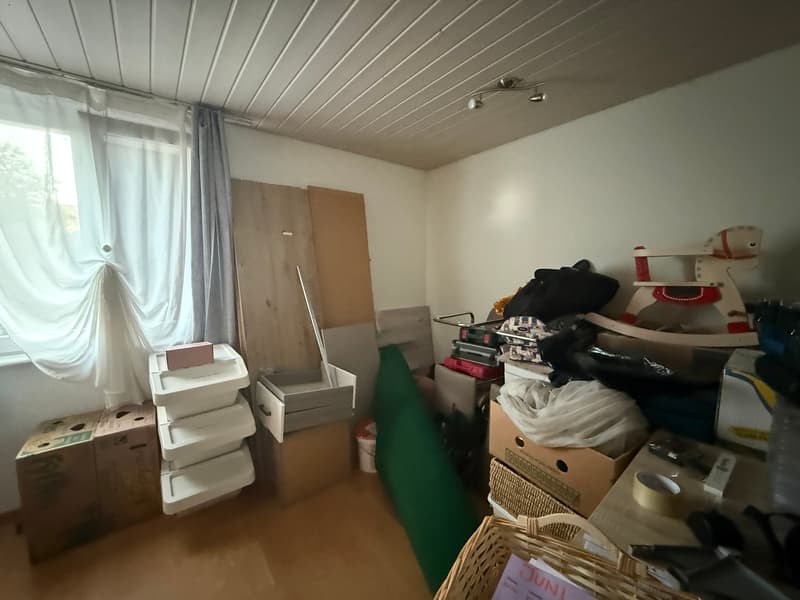 room with white walls, wooden floor, white ceiling, storage boxes, toys, white curtains, wooden door