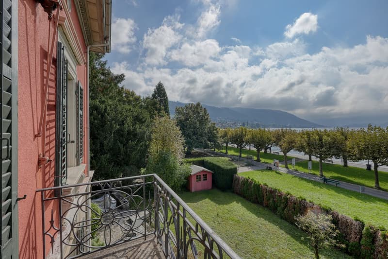 balcony, red building, green lawn, trees, mountains, lake