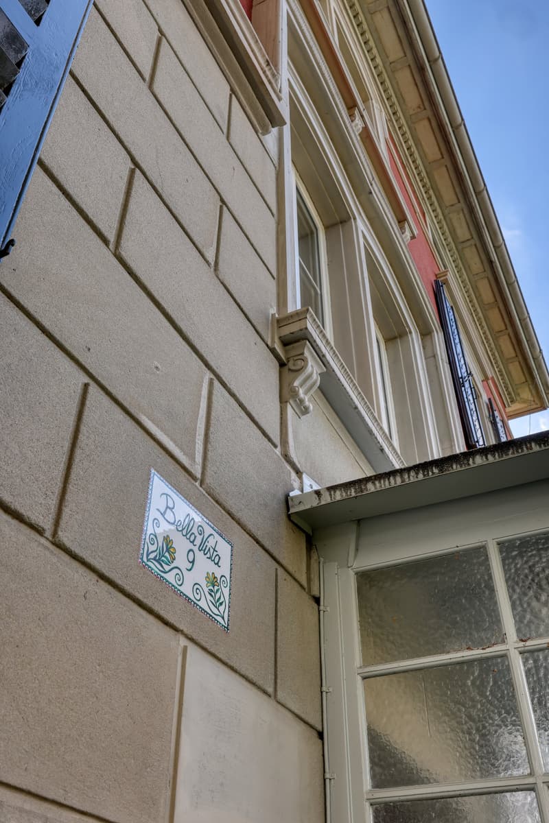 Facade of a building with a decorative sign reading 'Bella Vista 9', brick wall, glass window, and a small door.