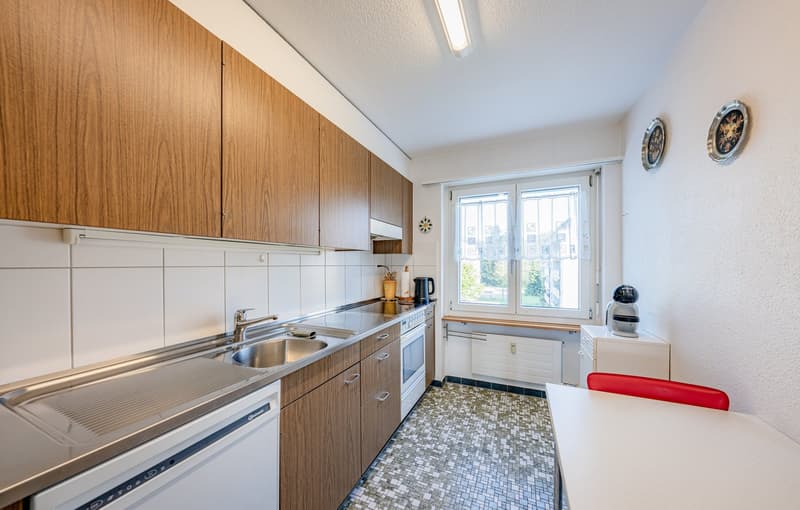 wooden cabinets, stainless steel countertop, sink, dishwasher, oven, coffee machine, window