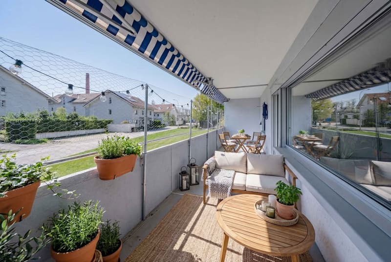 Balcony with a view, white sofa, wooden table, potted plants, outdoor dining set, string lights