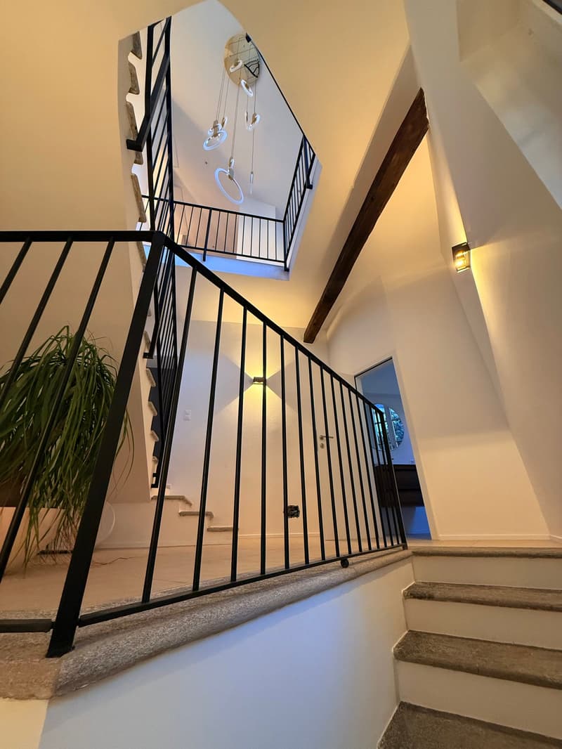 modern staircase in multistory house, two levels visible, white walls, wooden floor, glass banisters, open ceiling