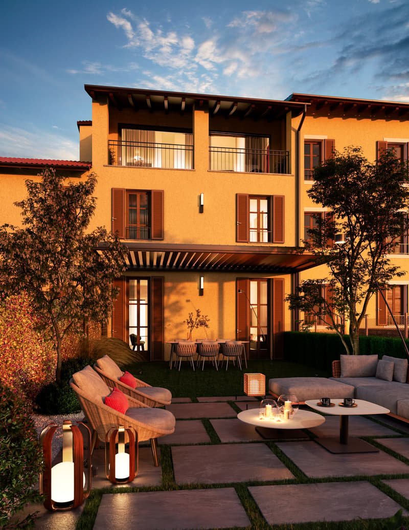 Outdoor patio with seating, dining table, trees, grass, lanterns, building with balconies and windows