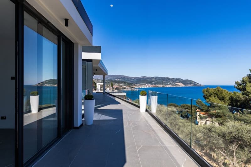 Modern house with glass walls, balcony with glass railings, ocean view, potted plants
