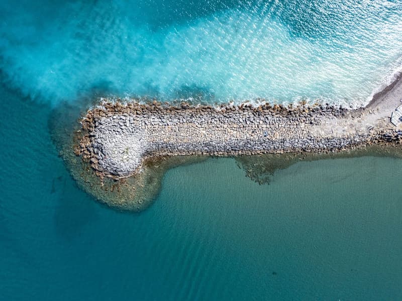 aerial view of a rocky shore with clear blue water