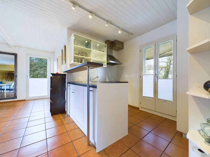 White tiled floor, modern kitchen layout, wooden countertop, integrated sink and faucet, built-in glass cabinets, large windows, white ceiling